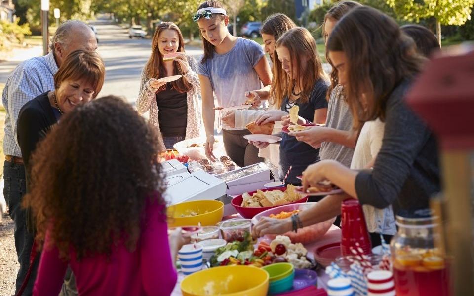 Image shows neighbours eating together at a street party