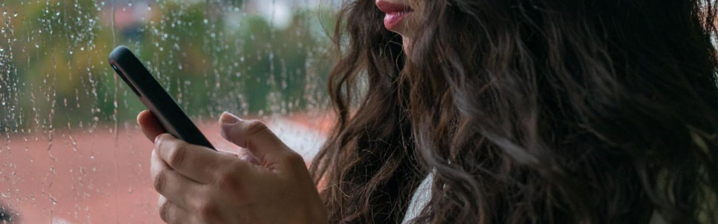 Image shows a close up of a woman holding a phone 