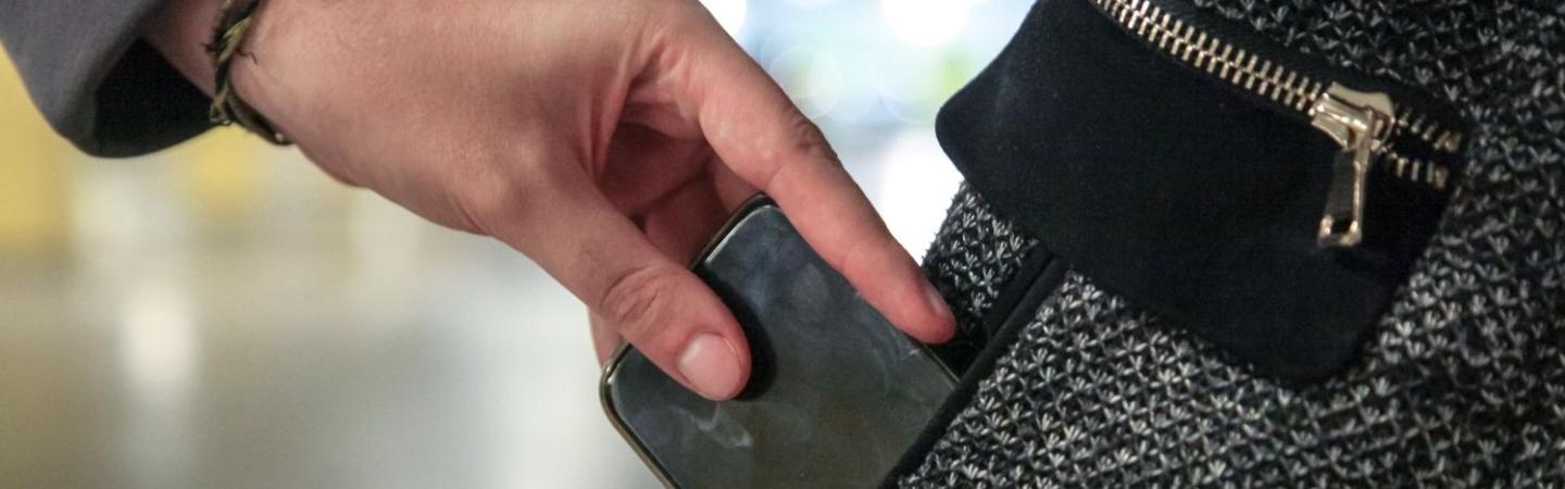 Image shows a person taking a mobile phone from a pocket